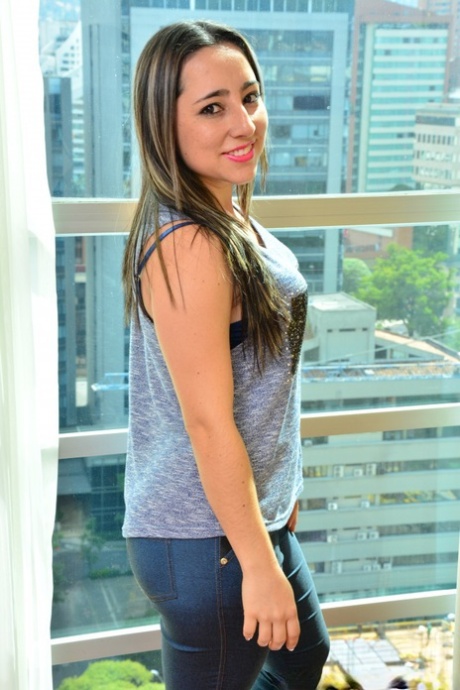 Tentadora belleza latina se quita los jeans para mostrar su gran culo junto a la ventana